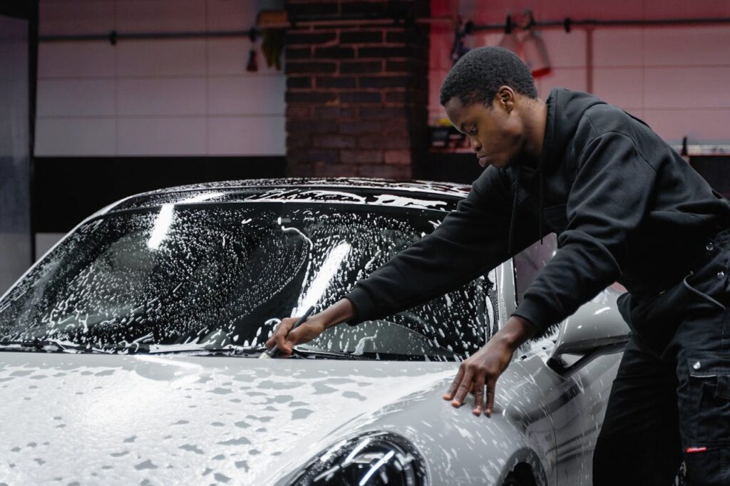 man-in-black-jacket-sitting-on-car-hood-6872150 Man in Black Jacket Sitting on Car Hood